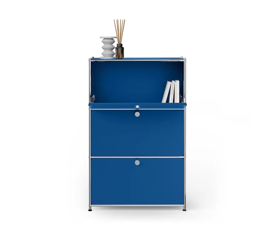 Blauer Modulschrank mit Chromrahmen. Auf der oberen Fläche stehen eine weiße Skulptur und ein Diffusor. Ein offenes Fach darunter enthält Bücher. Eine offene Klappe ist über einer geschlossenen Schublade.