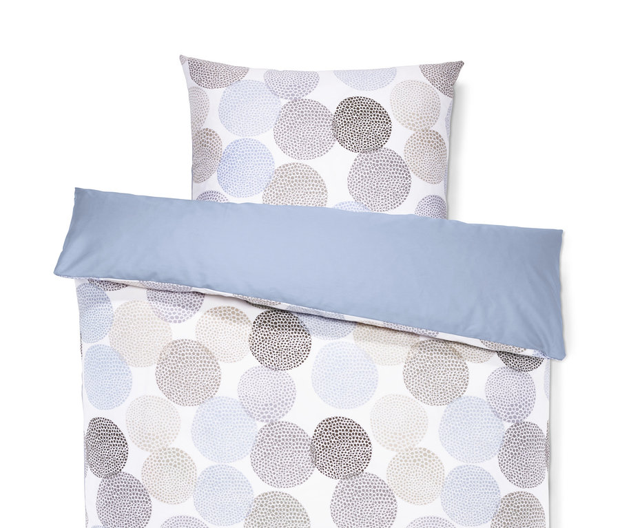 Auf einem weißen Hintergrund liegt eine Satin-Wendebettwäsche in Normalgröße mit blauem Rand und einem Muster aus gepunkteten Kreisen.
