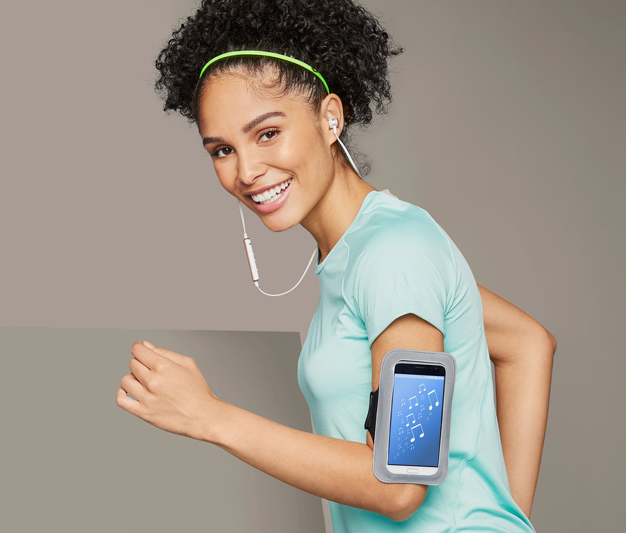 Frau läuft mit einem Smartphone-Sportarmband am Arm.