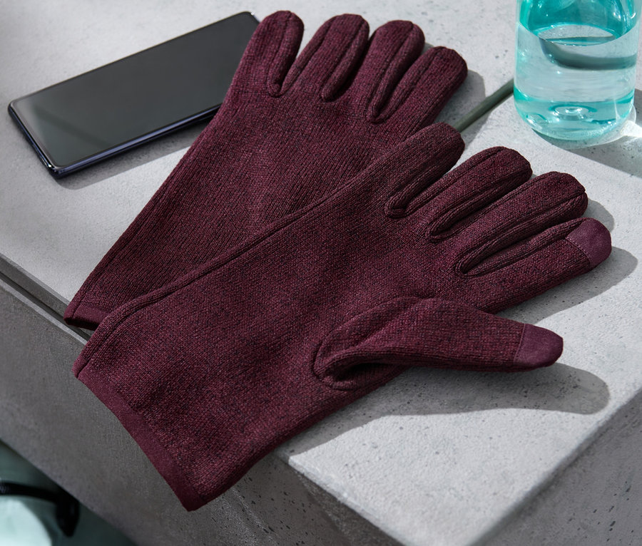 Auf einer grauen Fläche liegen Strickfleece-Handschuhe, ein Handy und eine Wasserflasche.