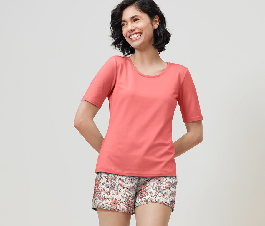 Lächelnde Frau trägt einen Shorty-Pyjama in Papaya.