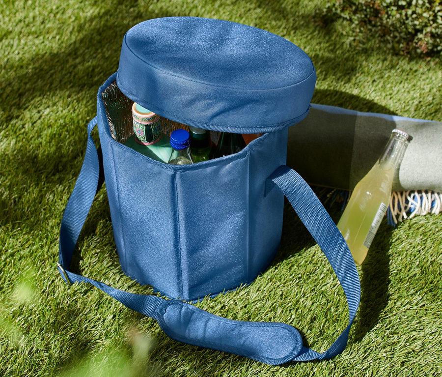 Eine blaue 2-in-1-Kühltasche steht auf dem Rasen, teilweise geöffnet, mit Flaschen im Inneren.