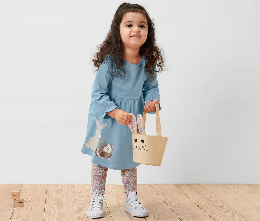 Mädchen im Kleinkind-Jerseykleid hält eine Tasche mit Hasenohren.