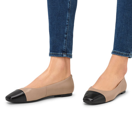 Beine in Jeans und Leder-Ballerinas.