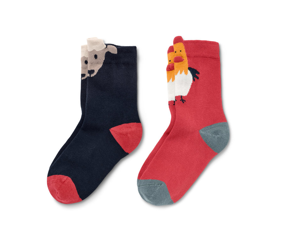 Zwei Paar 3D Kleinkind-Socken, davon ein Paar dunkelblau mit Schaf-Motiv und ein Paar rot mit Hühner-Motiv.