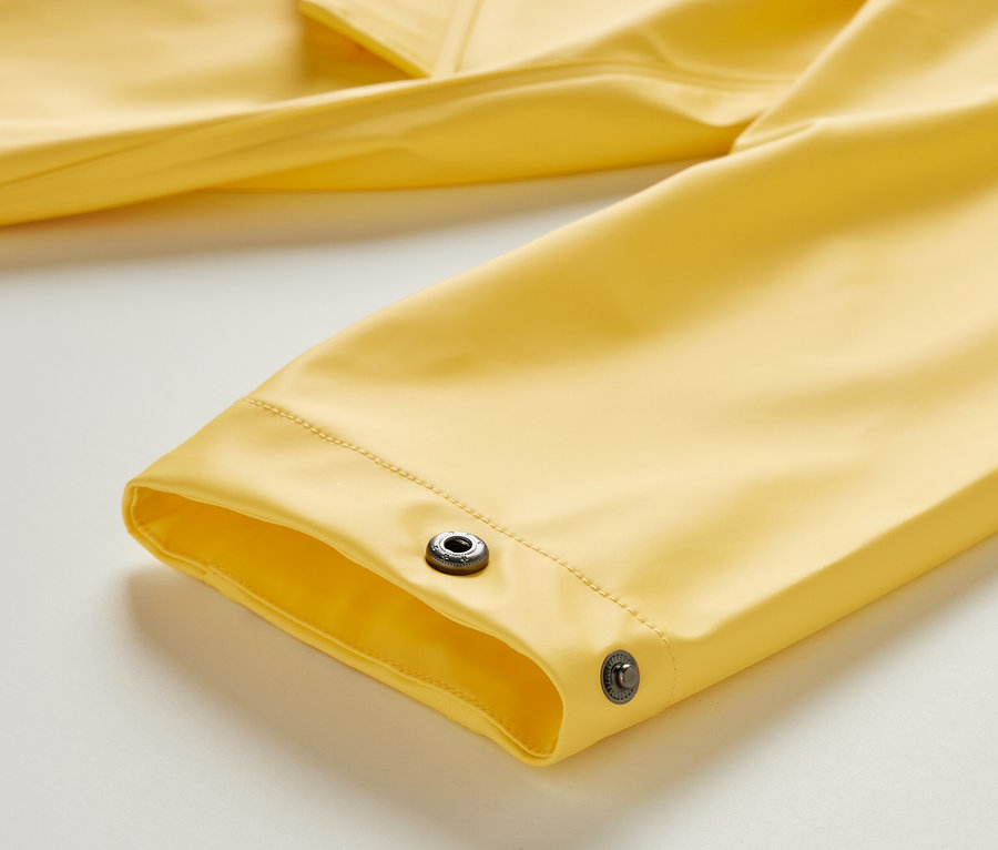 Detailansicht eines gelben Regenparkas »Friesennerz« mit Druckknöpfen am Ärmel.