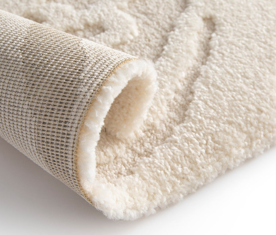 Detailansicht eines cremefarbenen Teppichs »Cosmo «Waves, der teilweise aufgerollt ist und die Textur zeigt.