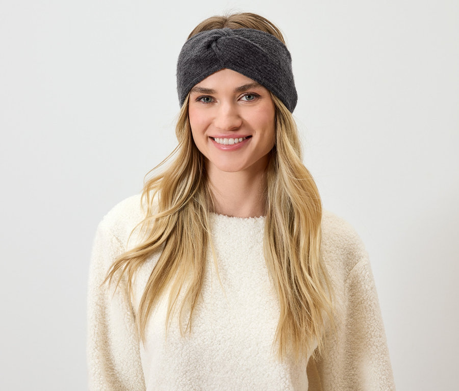 Frau mit blonden Haaren und grauem Stirnband lächelt.