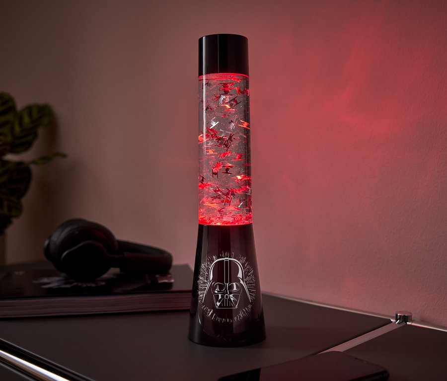Eine schwarze Lavalampe mit Darth Vader-Motiv auf dem Sockel und rotem Glitter im Inneren steht auf einem Tisch.