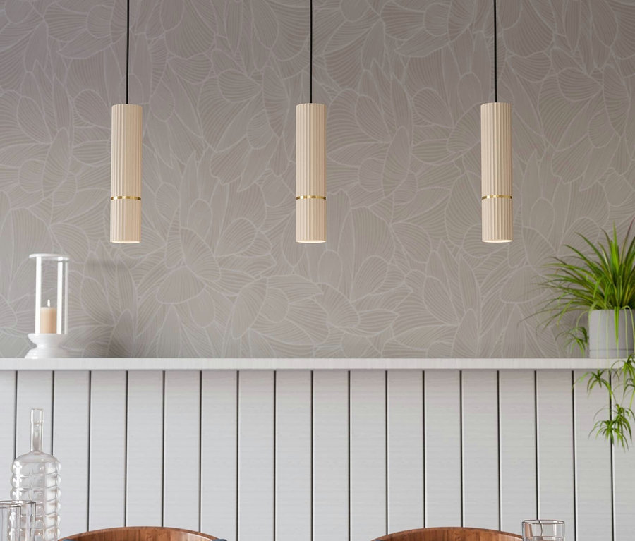 Drei Lampen hängen über einem Holztisch mit Stühlen, auf dem Wassergläser stehen.