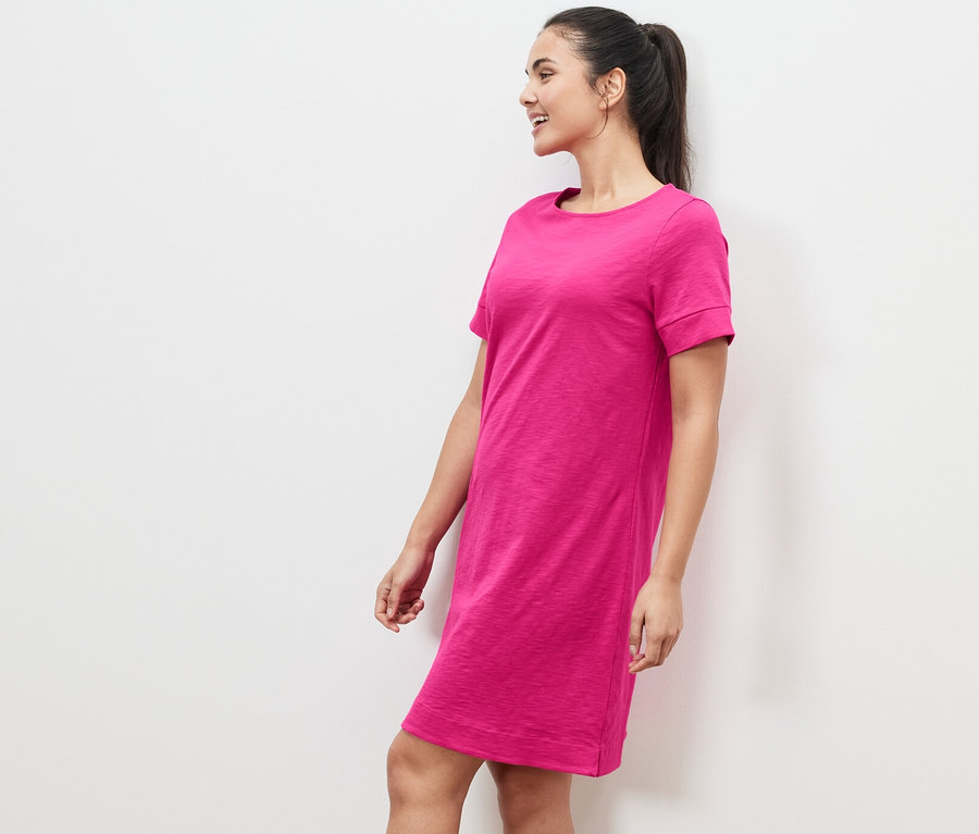 Frau steht seitlich in einem pinken Jerseykleid.