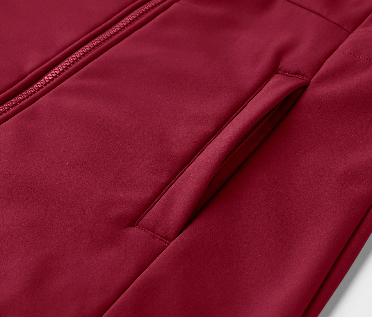 Detailansicht eines dunkelroten Softshellmantels mit Reißverschluss und Tasche.