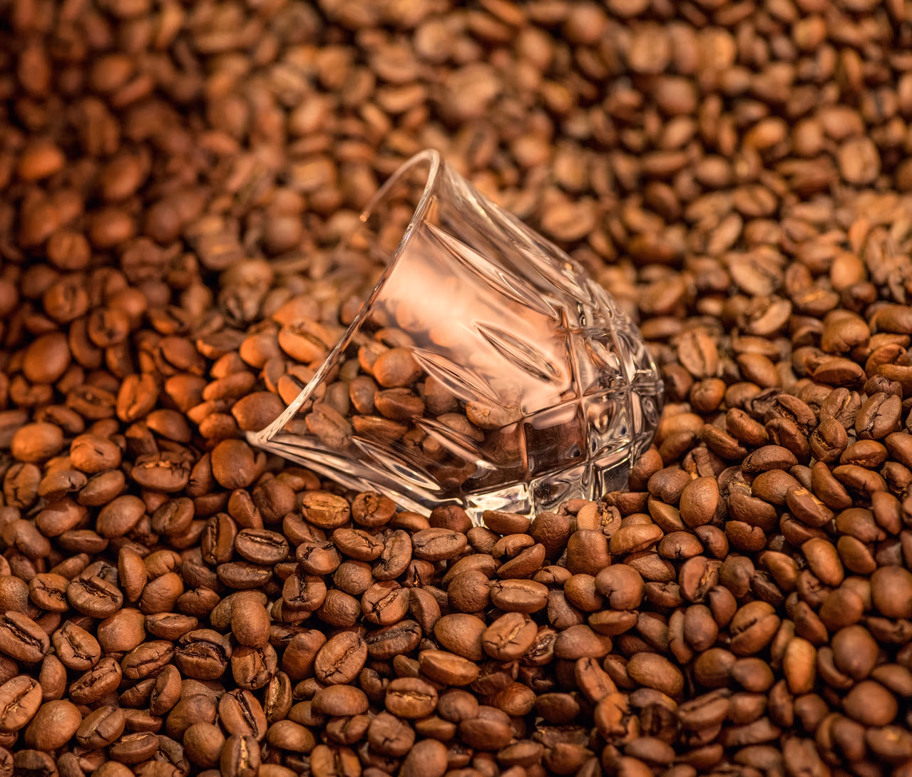 Ein umgekipptes, transparentes Nachtmann Espressoglas »Noblesse« liegt auf Kaffeebohnen.