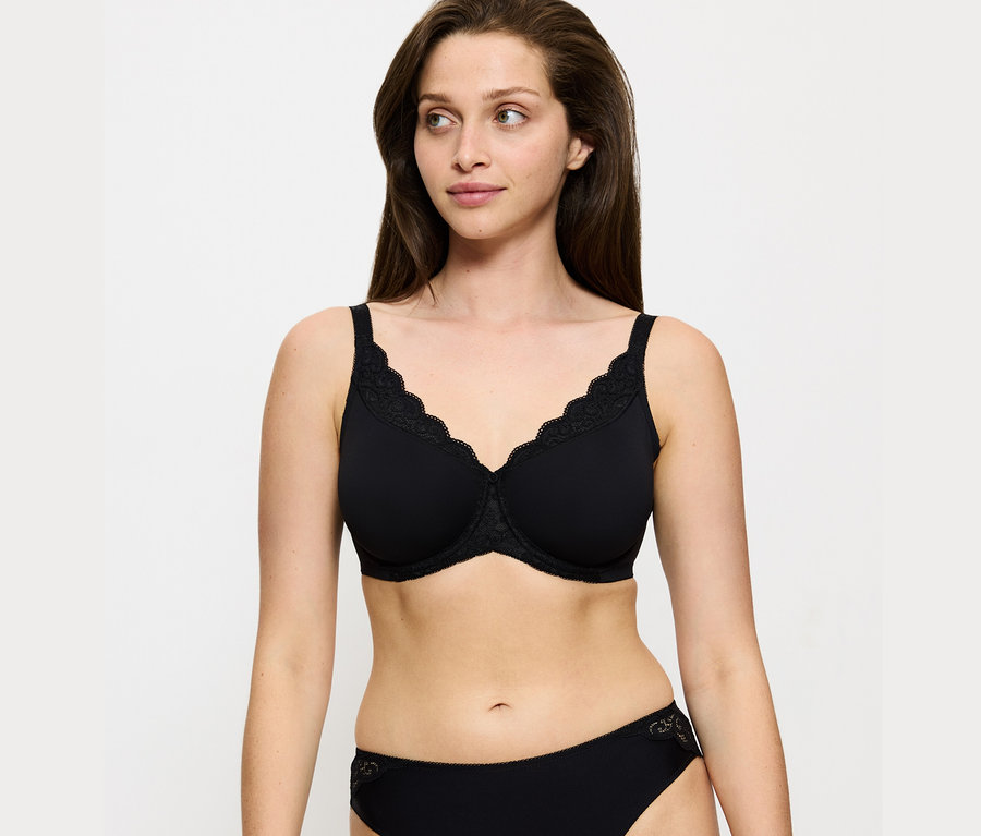 Frau trägt einen schwarzen Triumph Amourette Minimizer-BH und eine schwarze Unterhose.