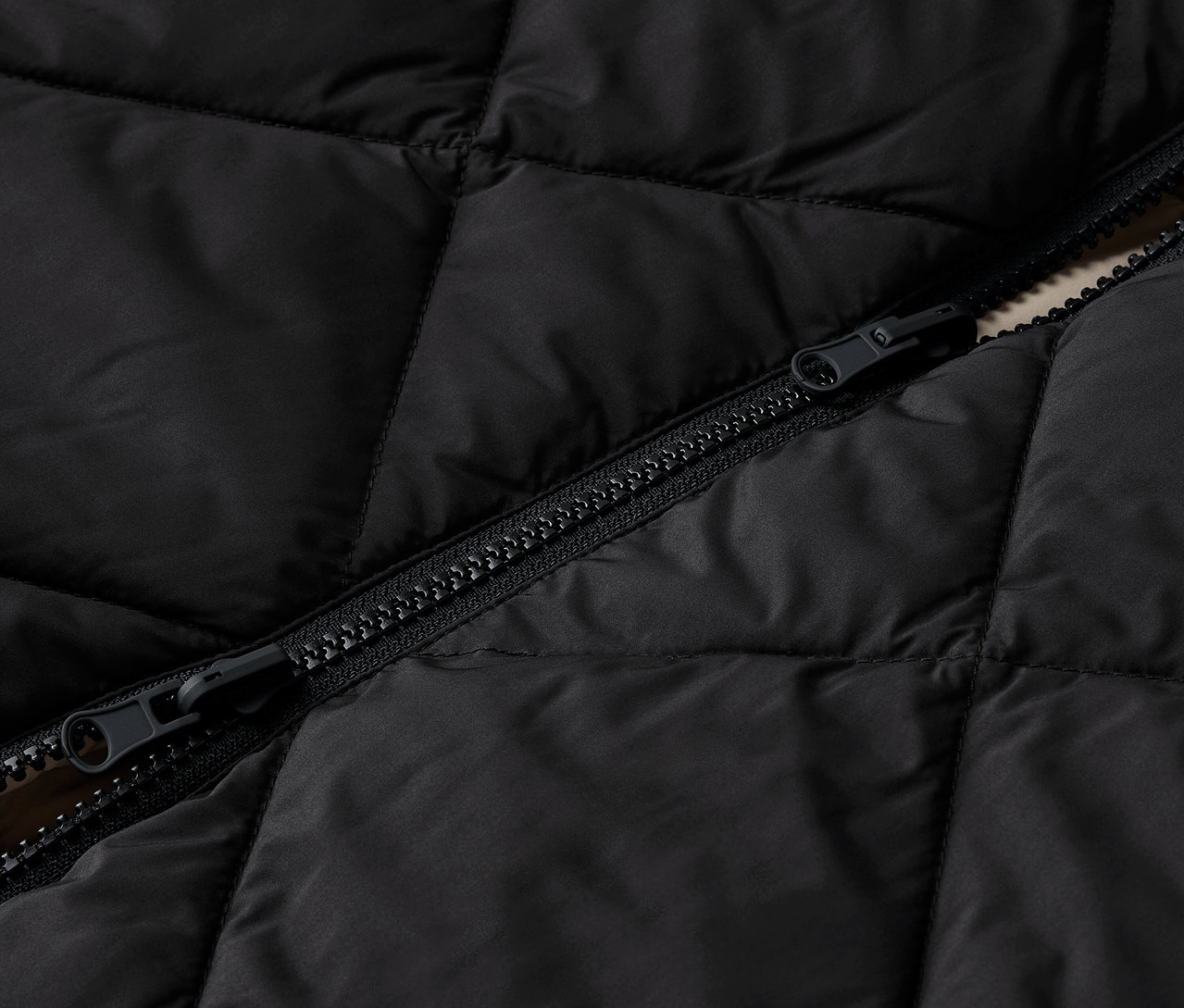 Detailaufnahme einer schwarzen Steppjacke mit Reißverschluss.