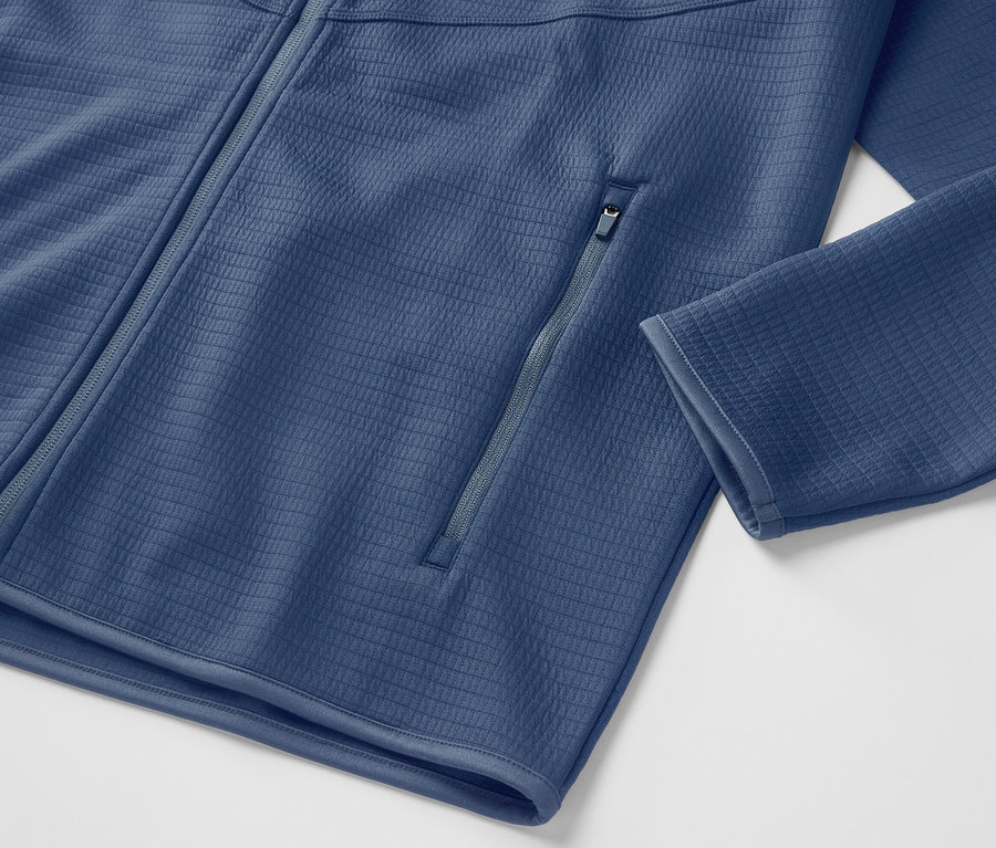 Detailansicht einer blauen Funktionsjacke mit Reißverschluss.