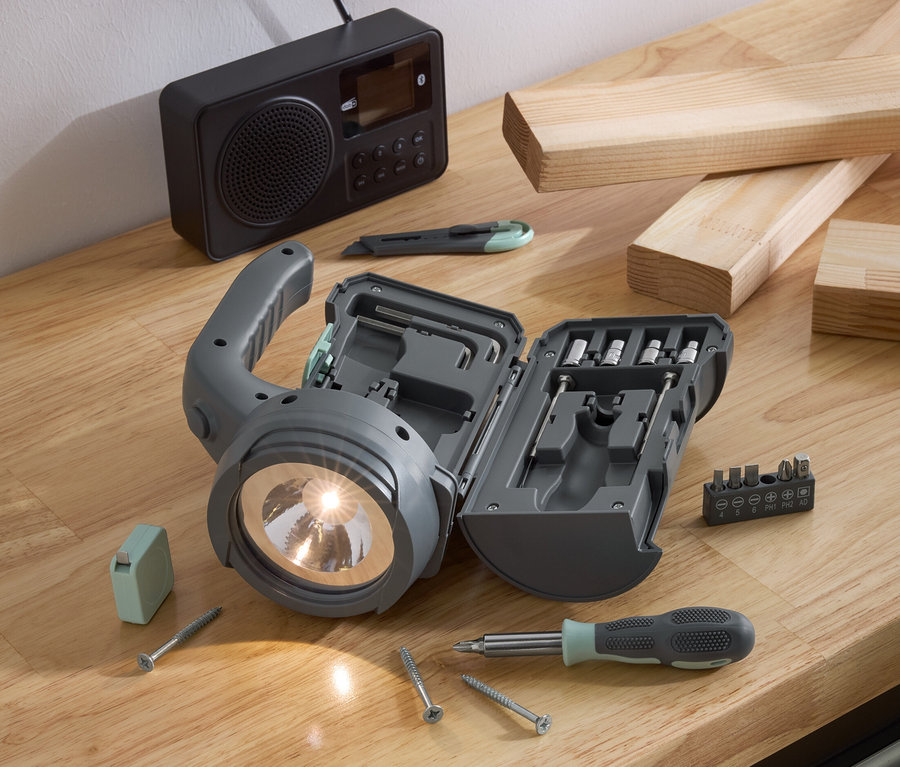 17-in-1-LED-Multifunktionsleuchte mit Zubehör auf einem Holztisch.