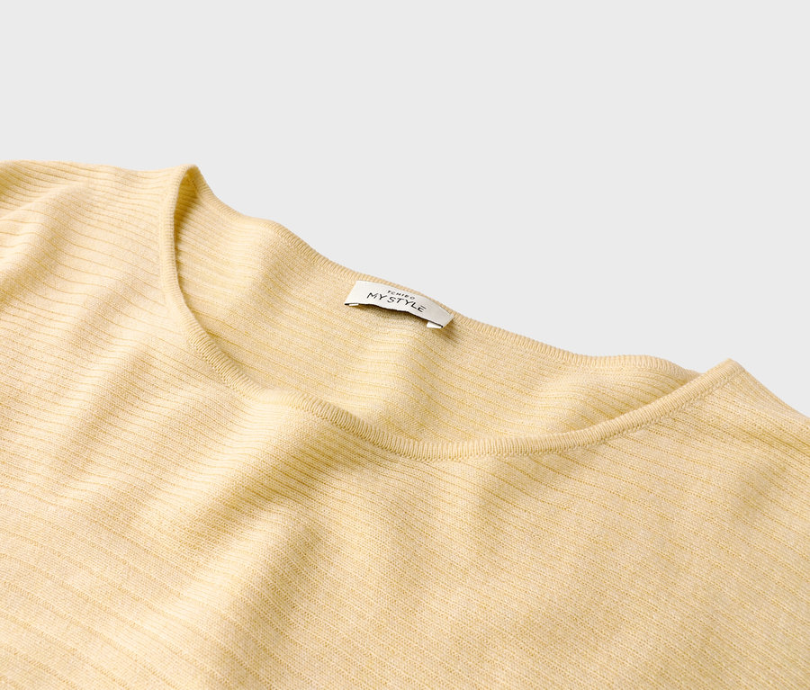 Nahaufnahme eines hellgelben gerippten Pullovers mit einem Etikett mit der Aufschrift "ICHIGO MYSTYLE".
