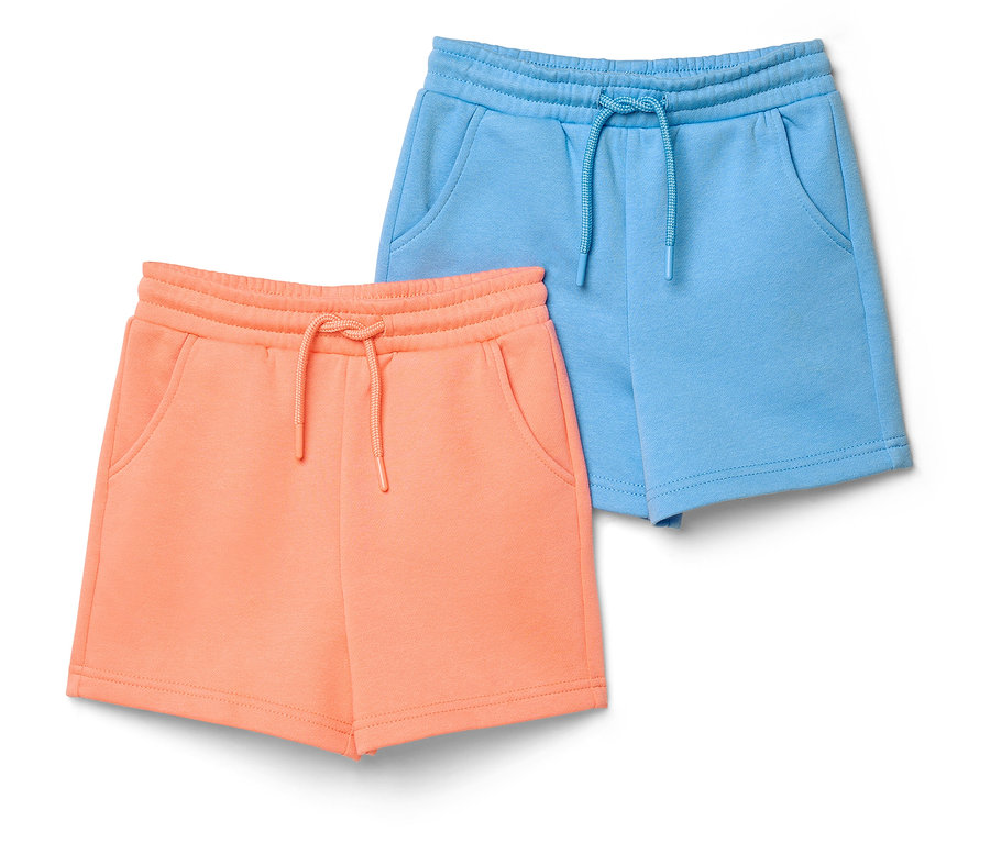 Zwei Kinder-Sweatshorts mit angerauter Innenseite: eine pfirsichfarbene und eine hellblaue, beide mit Gummibund, Kordelzug und Taschen.
