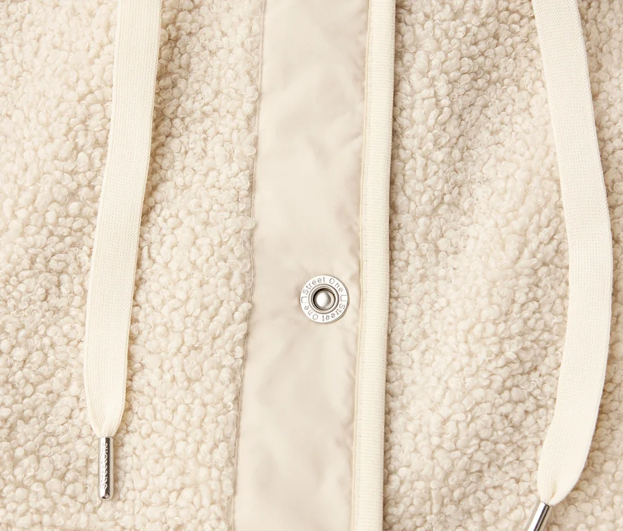 Detailansicht einer Street One Teddyjacke mit abnehmbarer Kapuze in Beige, mit Kordelzug und Knöpfen.