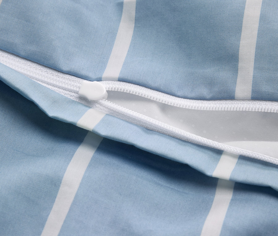 Nahaufnahme eines teilweise geöffneten Bettbezugs mit blau-weißem Streifenmuster und weißem Reißverschluss.