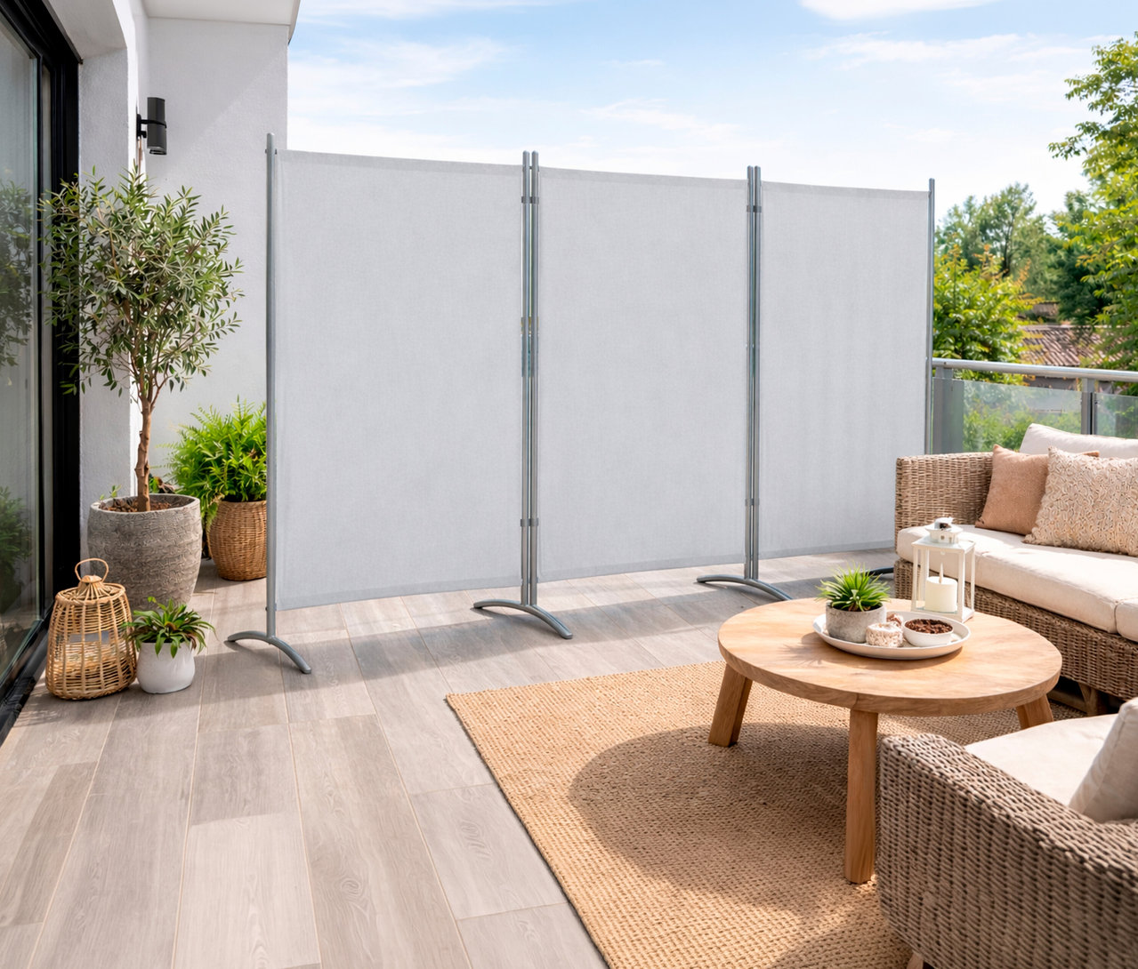 Auf einer Terrasse steht eine helle Leco 3-teilige Stellwand neben einem Rattansofa und einem Tisch.