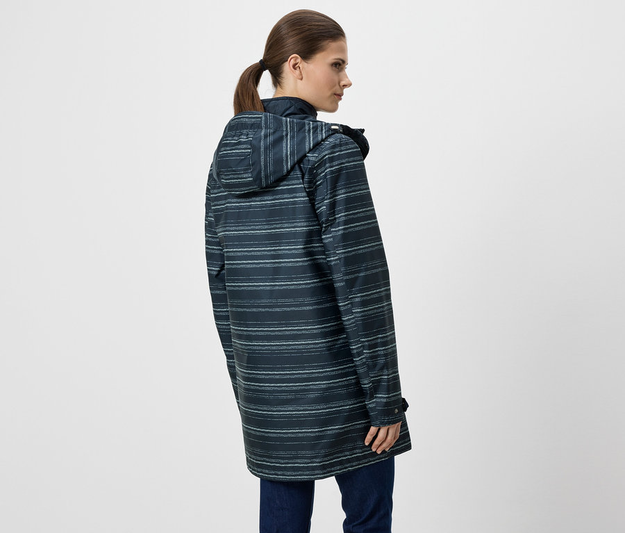 Frau von hinten in blau gestreifter Regenjacke mit Kapuze und Jeans vor weißem Hintergrund.