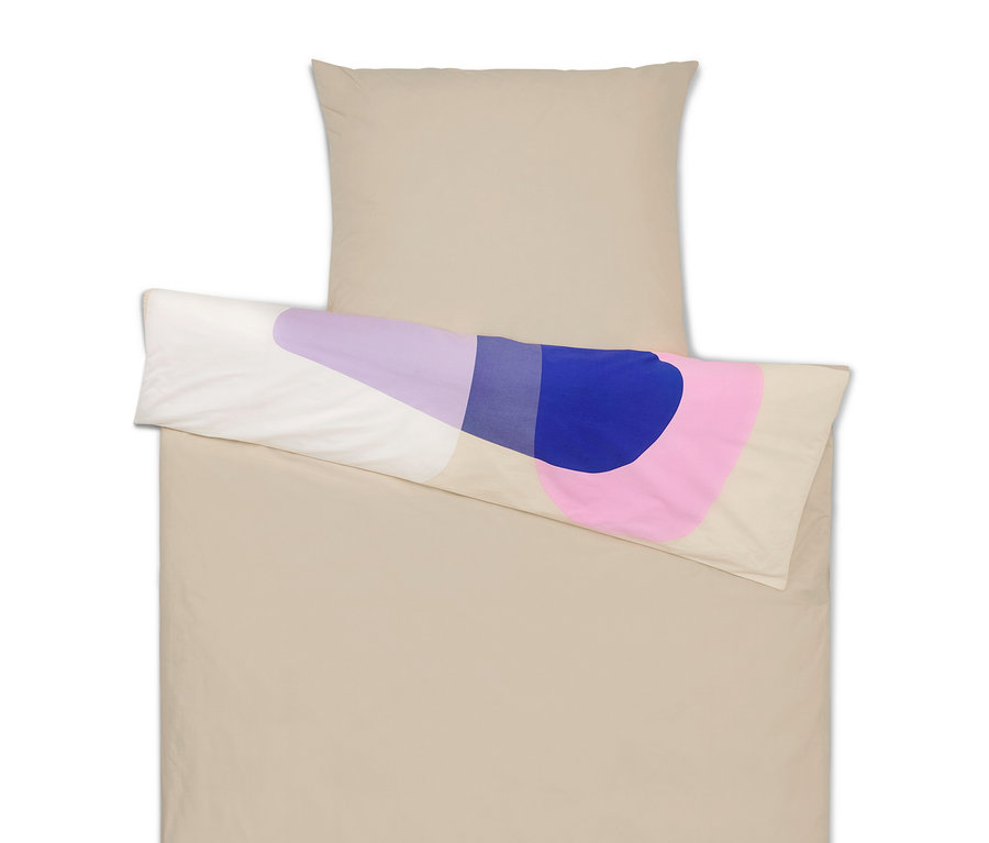 Beige Bettwäsche mit Kopfkissen und einem Kissen mit abstrakten lilafarbenen, blauen und rosa Formen.