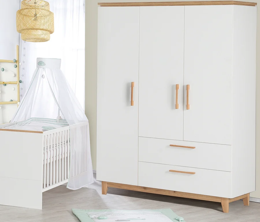 Ein Kinderzimmer mit einem weißen Kinderbett mit Himmel, einem weißen dreitürigen Kleiderschrank und einer Spieldecke auf dem Boden.