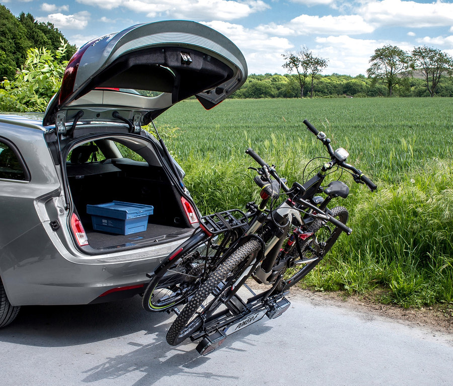 Zwei Fahrräder auf einem »Poker-F« Fahrradträger an einem grauen Auto mit geöffnetem Kofferraum.