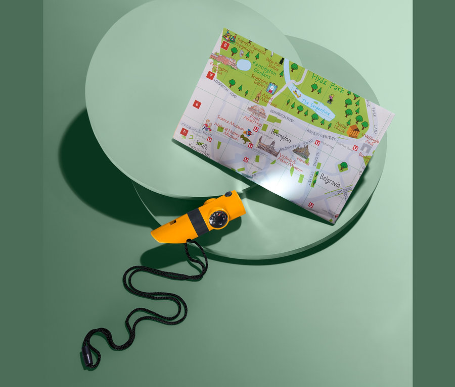 Ein gelbes, kompaktes 7-in-1-Outdoor-Tool liegt neben einer London-Karte auf einem grünen Hintergrund.