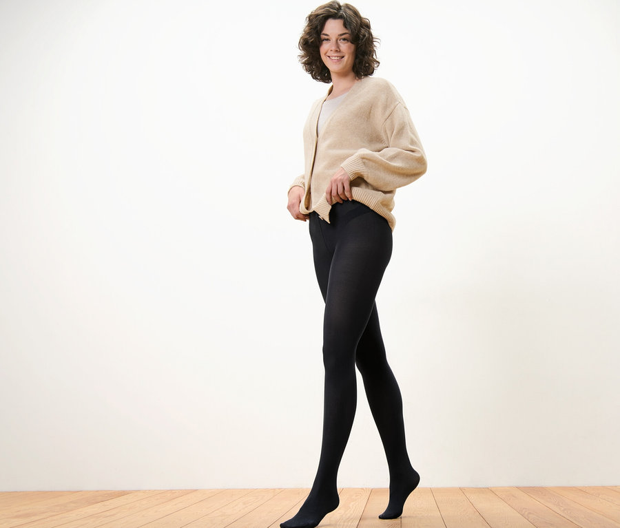 Frau trägt und richtet eine schwarze Feinstrumpfhose, 80 DEN.