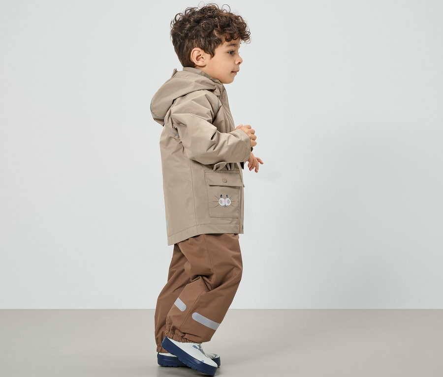 Junge trägt eine braune Kinder-Regenjacke.