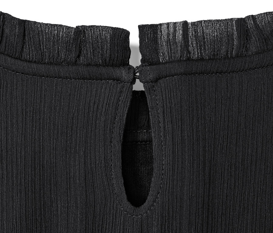 Detailansicht eines Kinder-Chiffonkleids mit Rüschen am Kragen und Tropfenausschnitt.