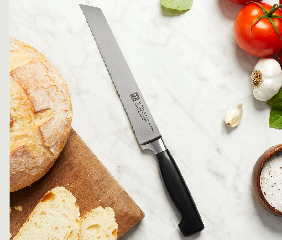 Brot und Tomaten mit ZWILLING Brotmesser auf Marmoroberfläche.