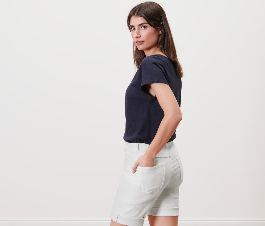 Frau posiert seitlich in Denim-Shorts – Fit Lea und T-Shirt.