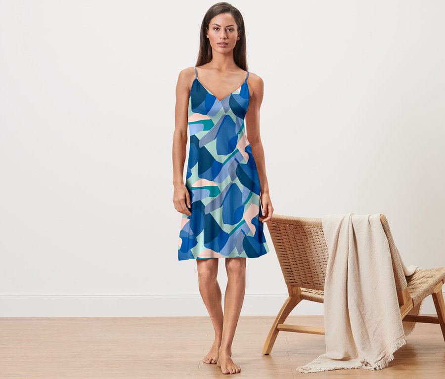 Frau steht barfuß da und trägt ein Trägernachthemd mit blauem Muster.