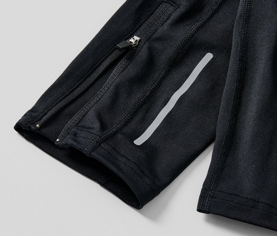 Detailaufnahme einer schwarzen Lauftight mit Reißverschluss und reflektierendem Streifen.