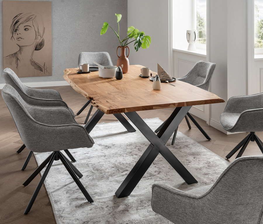 Ein Esstisch mit einer Holzplatte und Metallbeinen steht auf einem gemusterten Teppich, umgeben von sechs grauen Esszimmerstühlen.