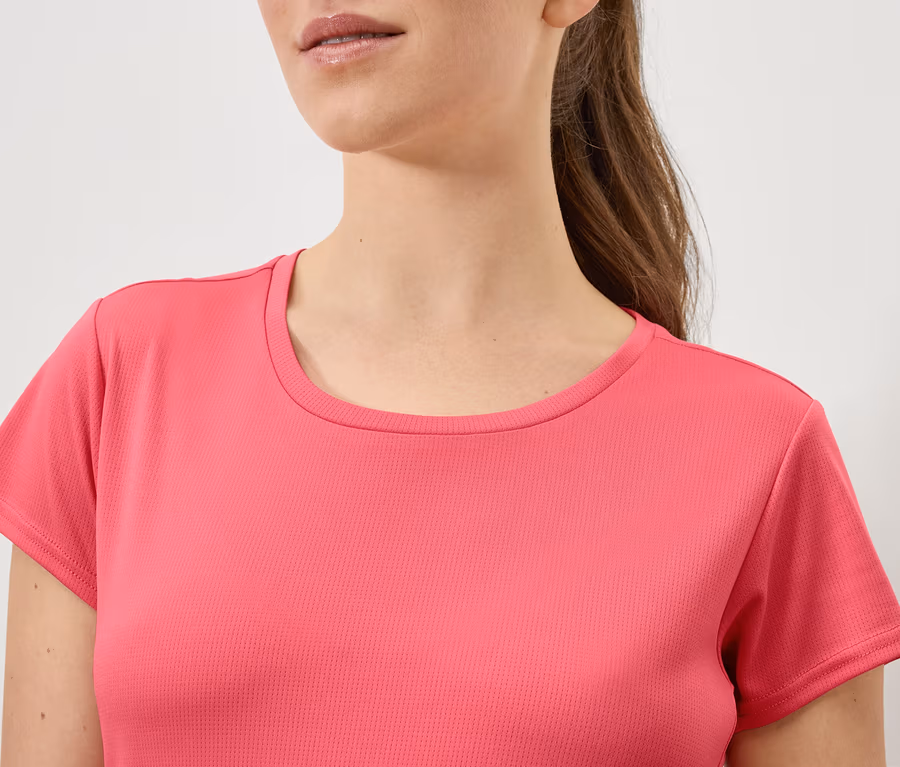 Oberkörper einer Frau mit braunen Haaren in einem pinkfarbenen T-Shirt.