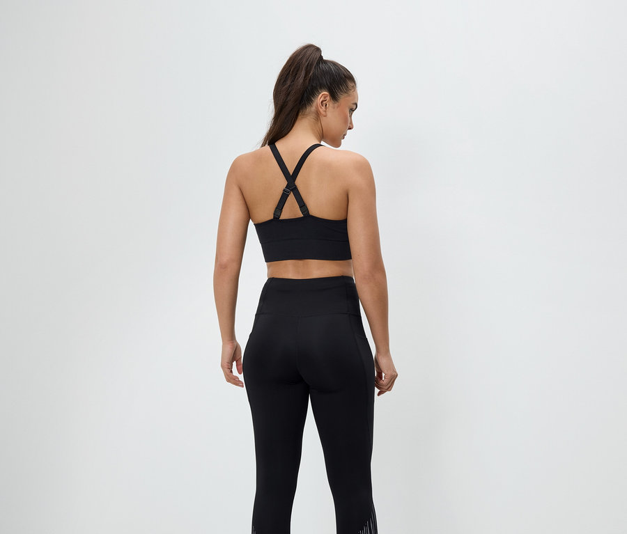 Rückansicht einer Frau in schwarzer Sportbekleidung, bestehend aus Sport-BH und Leggings.