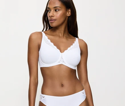 Eine Frau trägt einen weißen Triumph Amourette Minimizer-BH mit Spitzenbesatz und einen passenden Slip.