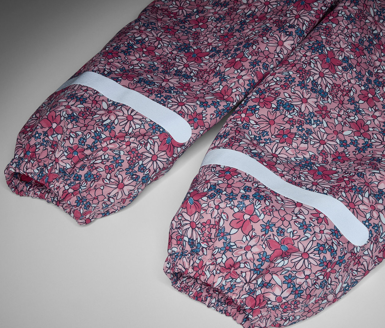 Detail einer Kinder-Thermo-Regenhose mit Blumenmuster und Reflektorstreifen.