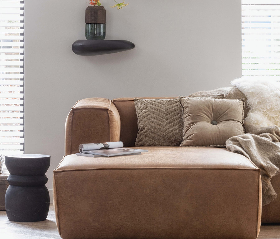 Braunes Sofa mit Kissen und schwarzer Woood Hocker »Bikkel« im Wohnzimmer.