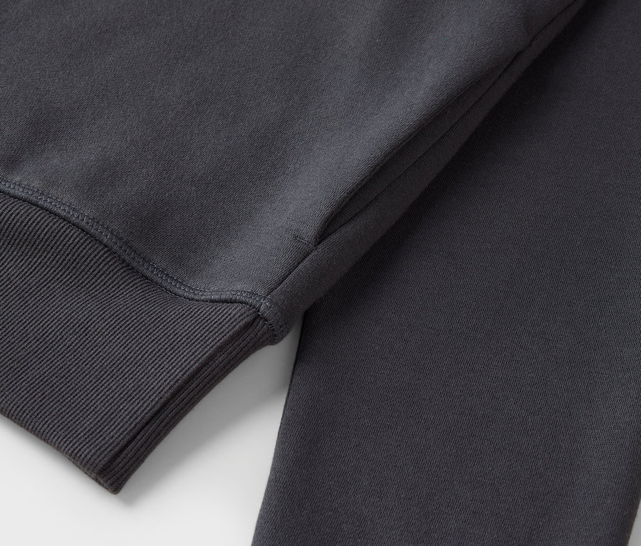 Detailaufnahme eines grauen Sweatshirts mit geripptem Ärmelbündchen.