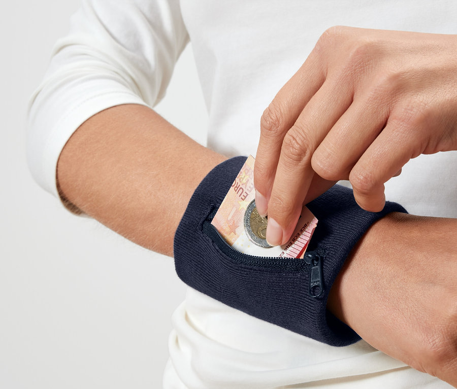 Eine Person legt eine Euro-Münze in eine marineblaue Armbandtasche.