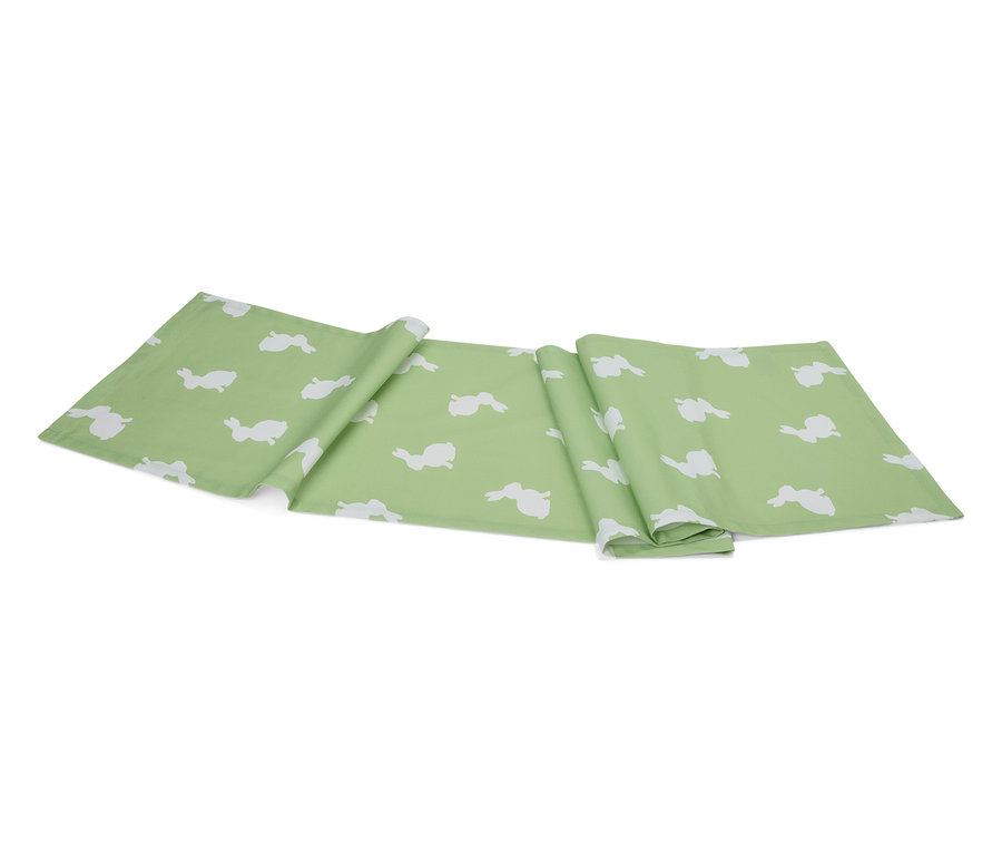 Ein hellgrüner Tischläufer mit einem weißen Hasenmuster liegt gefaltet auf einem weißen Hintergrund.