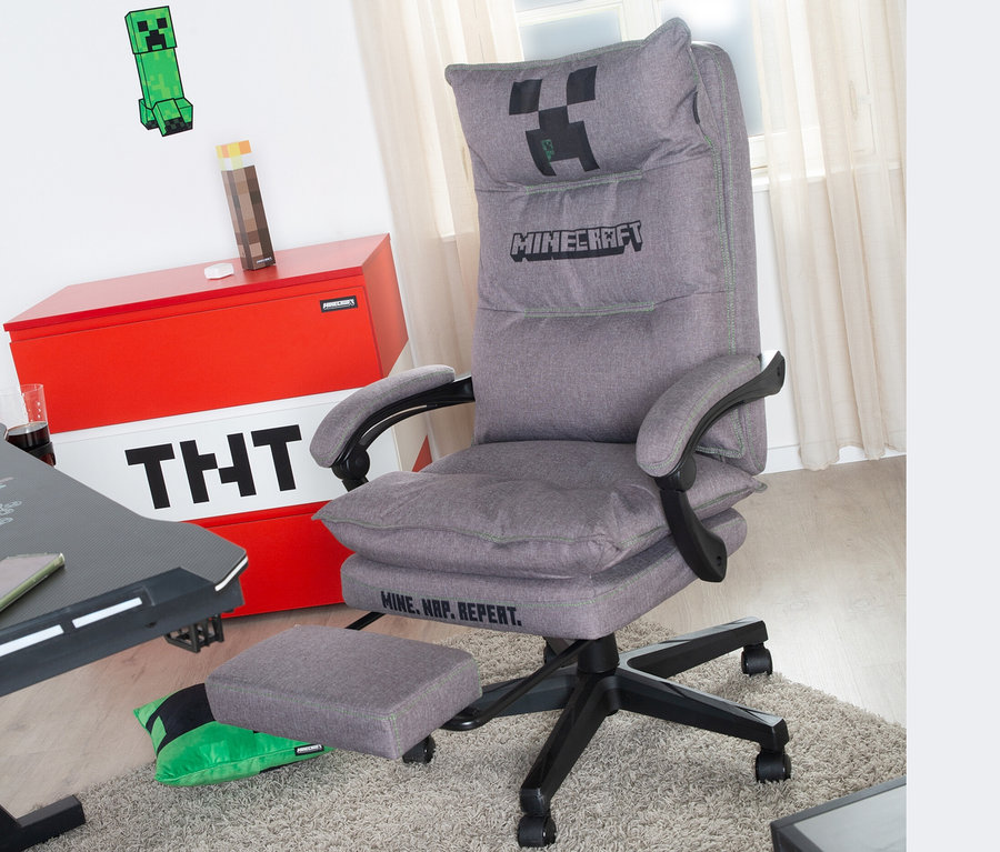 Grauer roba Minecraft Gaming-Stuhl mit Fußstütze steht auf einem Teppich. Im Hintergrund befinden sich eine Truhe mit TNT-Motiv und Minecraft-Dekoration.