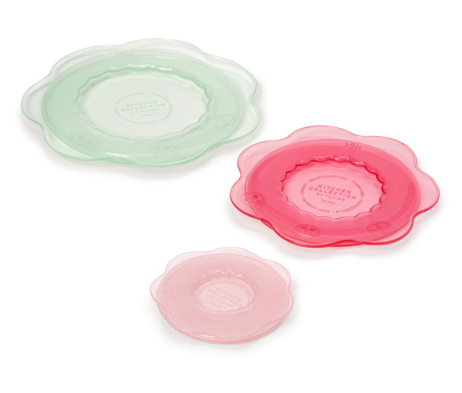 Drei Küchenabdeckungen in Grün, Pink und Rosa liegen auf einem weißen Hintergrund.