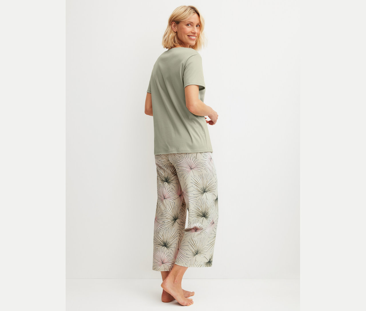 Frau trägt ein grünes T-Shirt und eine bedruckte Pyjamahose.
